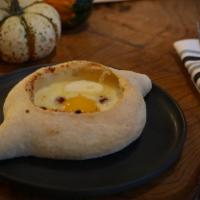 Adjaruli Cheese Pie · Open faced Georgian cheese bread with baked egg and cultured butter.