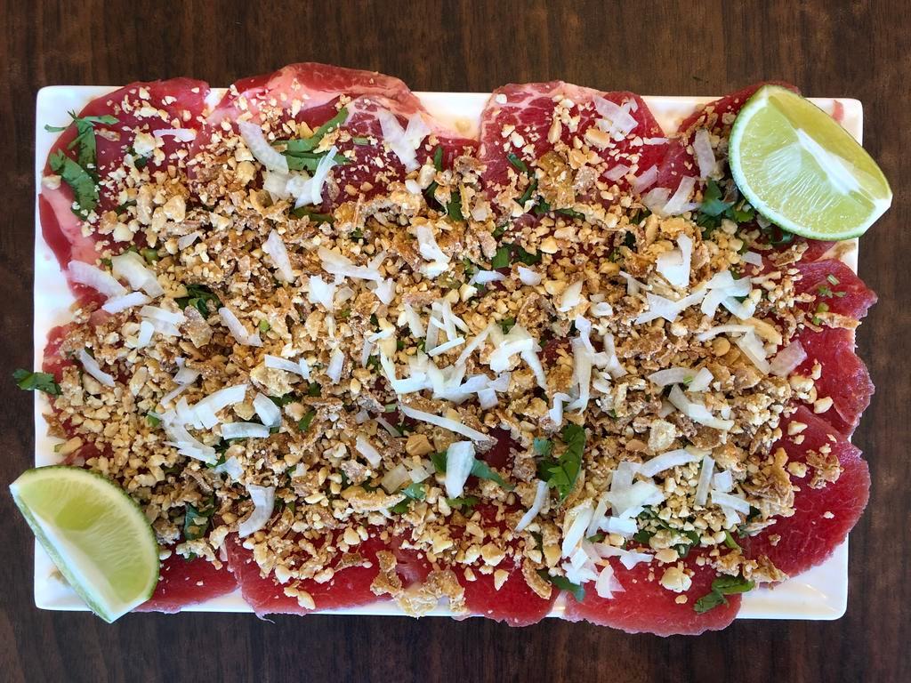 6. Vietnamese carpaccio (Filet mignon) · *Contains Peanuts* Sliced rare filet mignon topped w/ peanuts, onions, basil, and fresh, squeezed lime juice served with homemade fish sauce