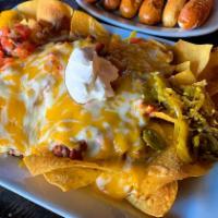 Nachos · Homemade tortilla chips topped with slow cooked chili, melted cheese, sour cream, jalapeno a...