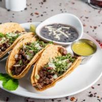 **Steak Tacos · Steak marinated and grilled, topped with onions, queso fresco, and cilantro. Sided with cila...