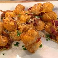 CHEDDAR BACON TOTS · Smothered in cheddar cheese and hickory smoked bacon bits topped with fresh chives and serve...