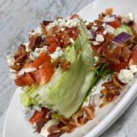 Wedge Salad · A wedge of crisp iceberg lettuce topped with chopped bacon, bleu cheese crumbles, diced toma...