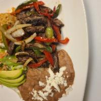 Skirt Steak Fajitas · Skirt steak fajitas served with Spanish onions, red and green pepper, Spanish rice, beans, a...