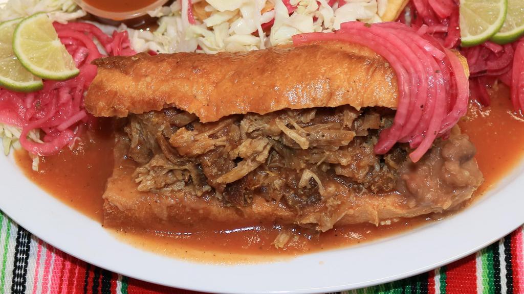 Torta Ahogada · Mexican Sandwich, with beans and carnitas (deep fried pork) topped with special tomato sauce, includes extra hot salsa, cured red onions and limes.
