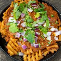 Curry Fries · Masala seasoned waffle fries topped with creamy curry sauce, red onions and fresh cilantro.