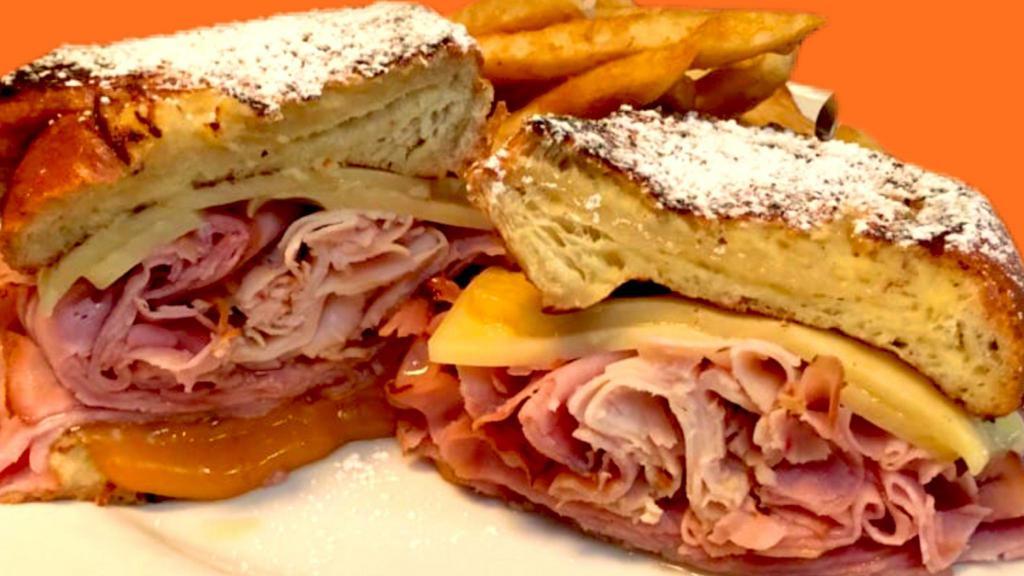 Monte Cristo · Challah bread French toast sandwich with honey smoked ham, smoked turkey, swiss, and cheddar cheese. Topped with powdered sugar. Served with hash browns.