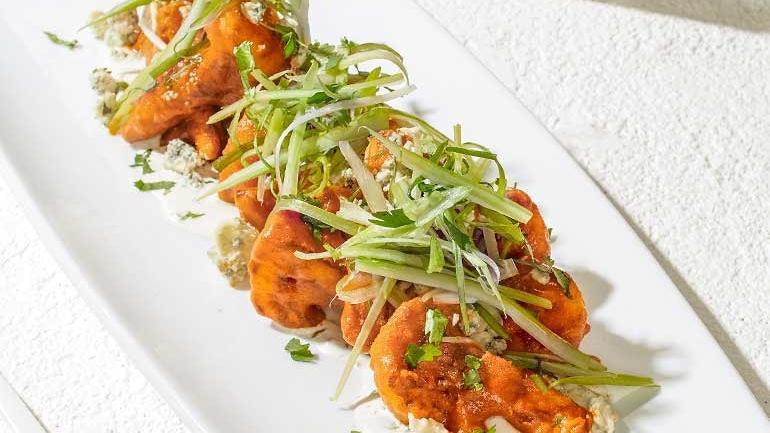 Spicy Buffalo Cauliflower · Fresh cauliflower florets buttermilk-battered and lightly fried, then tossed in housemade Sriracha buffalo sauce and topped with a. salad of celery, cilantro, scallions and Gorgonzola..