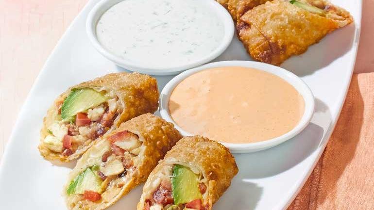 Catering Avocado Club Egg Rolls · Hand-wrapped crispy wonton rolls filled with avocado, chicken, tomato, Monterey Jack and Nueske’s applewood smoked bacon. Served with housemade ranchito sauce and herb ranch.  .