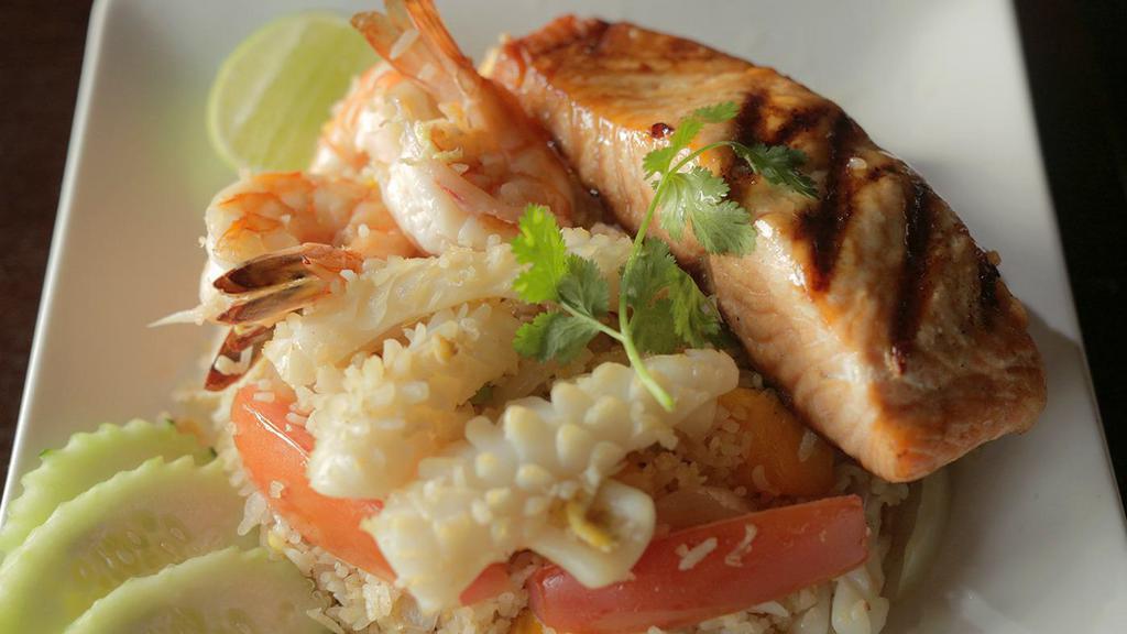 Seafood Mango Fried Rice · Fried rice with mango, onion, green onion, tomato, prawns, calamari topped with grilled salmon served with lime and fresh cucumber.
