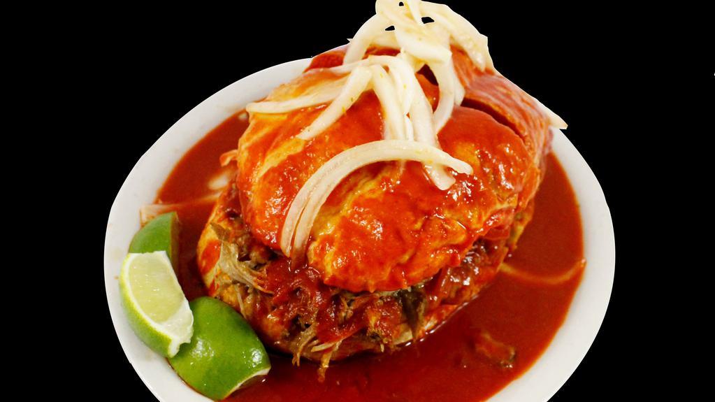 Torta Ahogada · A delicious piece of roll bread generously filled with homemade roasted pork, fried beans, tomato slices, topped with homemade spicy sauce, and onion slices.