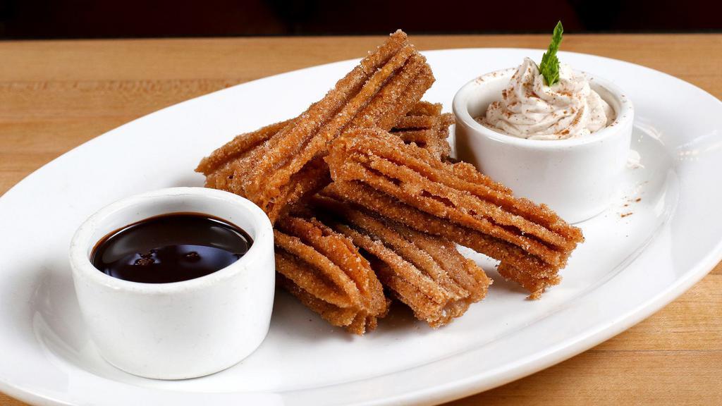 Churros · Homemade dulce de leche filled churros, whipped cream, and chocolate sauce.