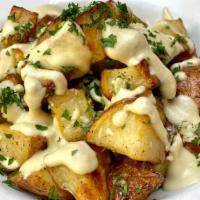 Vegan Cheesy Potatoes · roasted potatoes with house-made cashew vegan cheese sauce. Garnished with herbs.