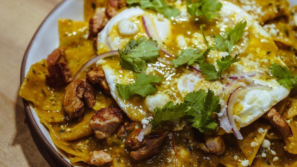 Chilaquiles Verdes · Traditional Mexican breakfast made with tortilla chips simmered in green sauce and topped with two fried eggs over-easy, queso fresco, cilantro and onions.