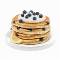 Lemon Ricotta Blueberry Protein Pancakes · Four fresh lemon ricotta blueberry protein pancakes loaded with blueberries, topped with cre...