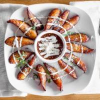 PLATANOS MACHO  · Fried plantains with black bean puree, topped with sour cream and cotija cheese.