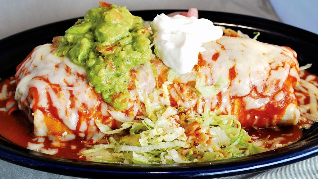 Super Famoso Carne Asada Burrito · Big burrito topped with enchiladaa sauce, cheese, sour cream and guacamole. Filled with rice and beans. Garnished with lettuce and cotija cheese. Steak with chopped tomatoes.