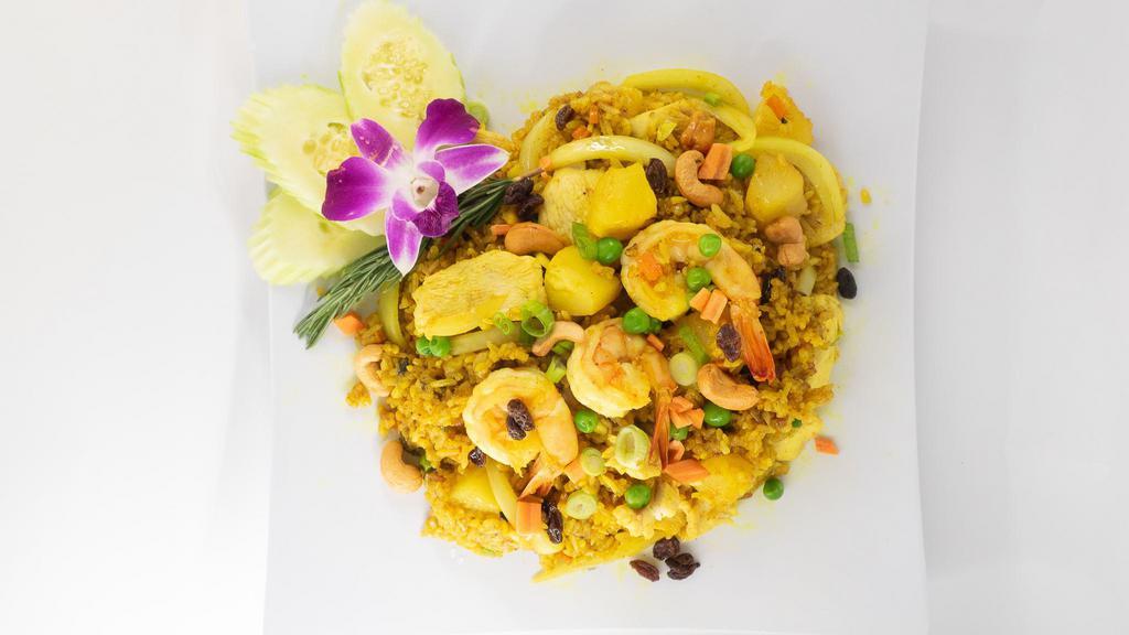 Pineapple Fried Rice · Fried rice with pineapple, curry powder, prawns, chicken, garlic, cashew nuts, raisins, onions, carrots, and peas.
