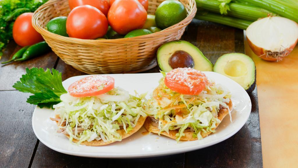 Tostadas · Refried beans, lettuce, tomato, onions, cotija cheese, and tomatillo sauce.