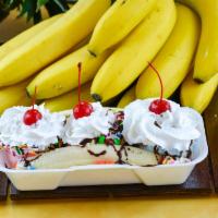Banana Split · A banana split in half covered with three scoops of ice cream. Topped with fudge drizzle, wh...