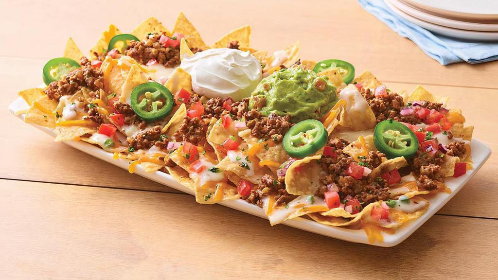 Neighborhood Nachos Beef · Freshly made white corn tortilla chips are topped with taco-seasoned ground beef, queso blanco, a blend of melted Cheddar cheeses, house-made pico de gallo, fresh jalapeños, chopped cilantro, sour cream and guacamole.