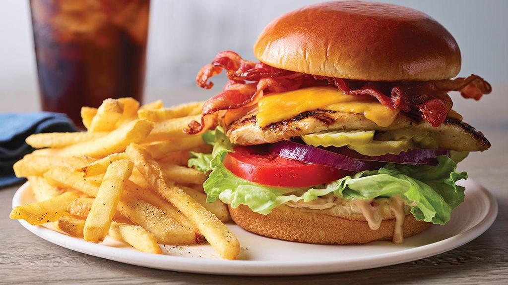 Bacon Cheddar Grilled Chicken Sandwich · Our grilled chicken breast is topped with two strips of Applewood-smoked bacon and Cheddar, then finished with tangy house-made BBQ ranch, crisp lettuce, tomato, onion and pickles on a Brioche bun.  Served with classic fries.
