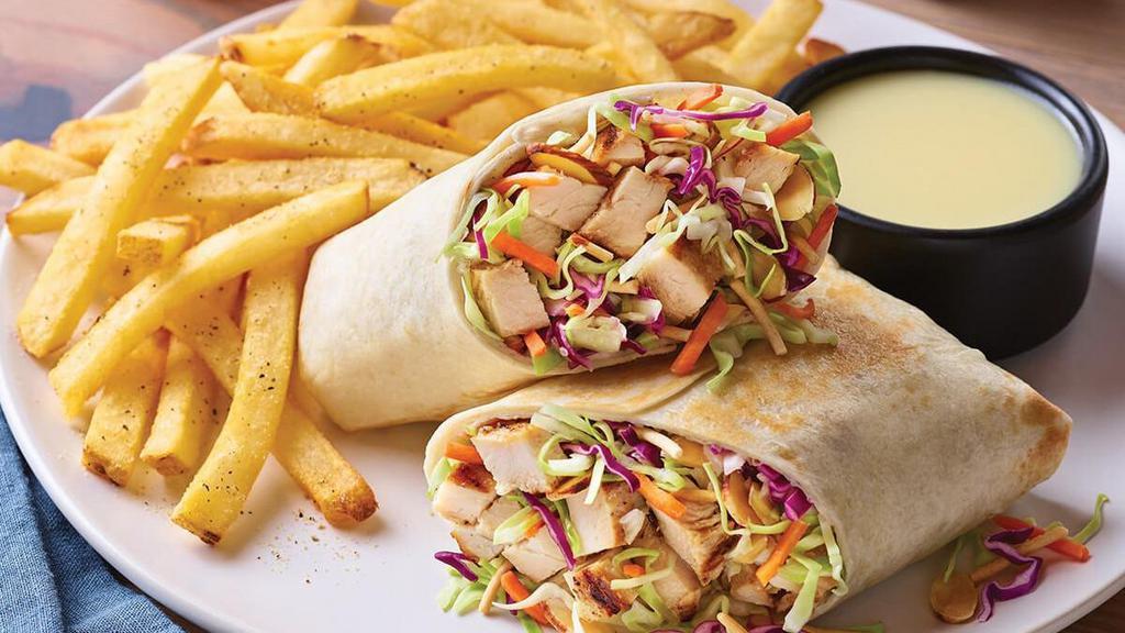 Oriental Grilled Chicken Salad Wrap · Our long-running favorite salad, all wrapped up. Our grilled chicken breast with fresh Asian greens, crunchy rice noodles and almonds rolled up in a warm flour tortilla. Served with classic fries and Oriental vinaigrette on the side. (Image shown with Crispy Chicken Tenders)