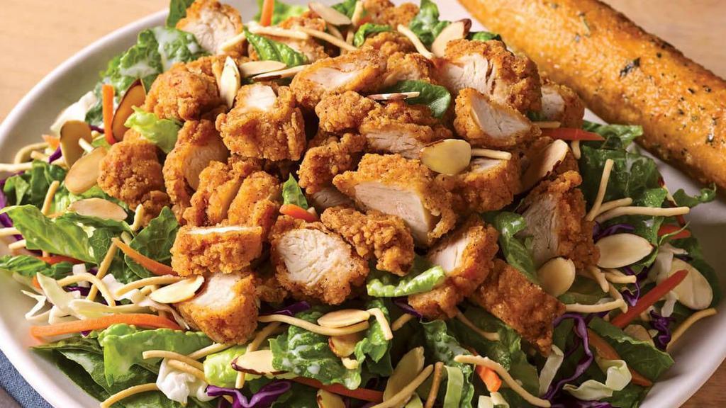 Oriental Chicken Salad · A long-running favorite, crispy breaded chicken tenders top a bed of fresh Asian greens, rice noodles and almonds tossed in our Oriental vinaigrette. Served with a golden brown signature breadstick brushed with buttery garlic and parsley.