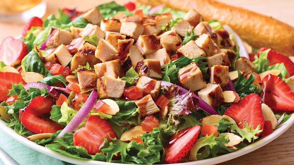 Strawberry Balsamic Chicken Salad · Tart, fresh and flavorful mixed greens with garden tomatoes, red onions, grilled chicken, sliced almonds, fresh strawberries and a drizzle of balsamic glaze. Served with a lemon olive oil vinaigrette on the side.