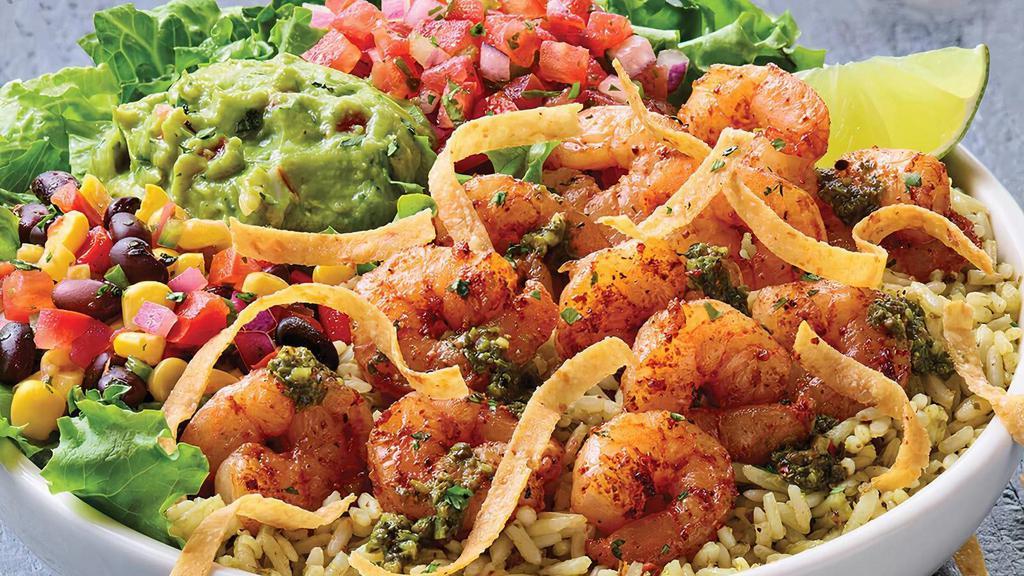 Tex-Mex Shrimp Bowl · Grilled chipotle lime shrimp on mixed greens and cilantro rice with house-made pico de gallo, black bean corn salsa and guacamole. Topped with chimichurri, tortilla strips and a fresh lime wedge.