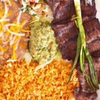 Carne Asada · Grilled steak with green onions on top with rice and beans.