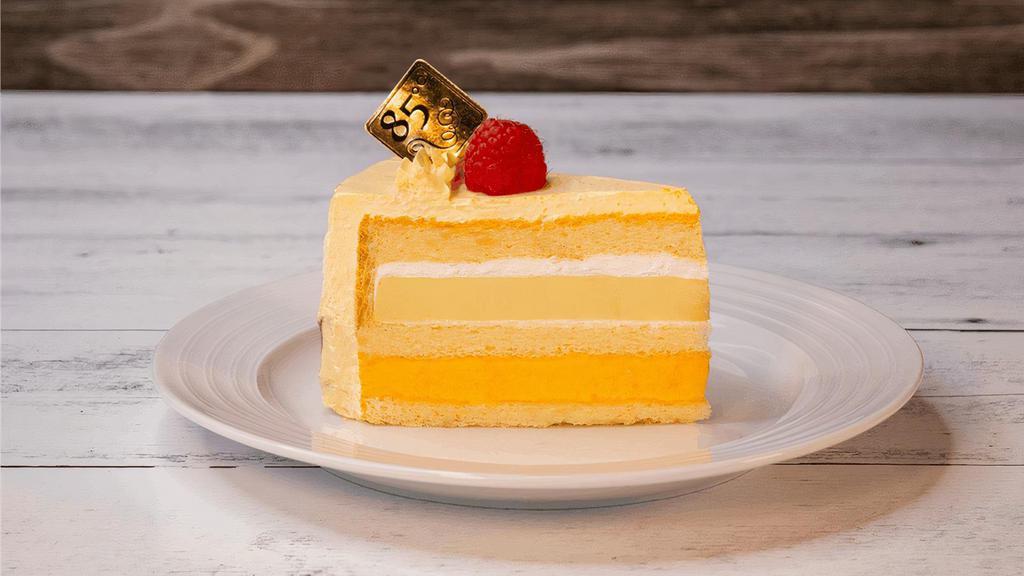 Mango Brulee | Slice · Vanilla sponge cake layered with vanilla brulee, mango mousse topped with a raspberry.