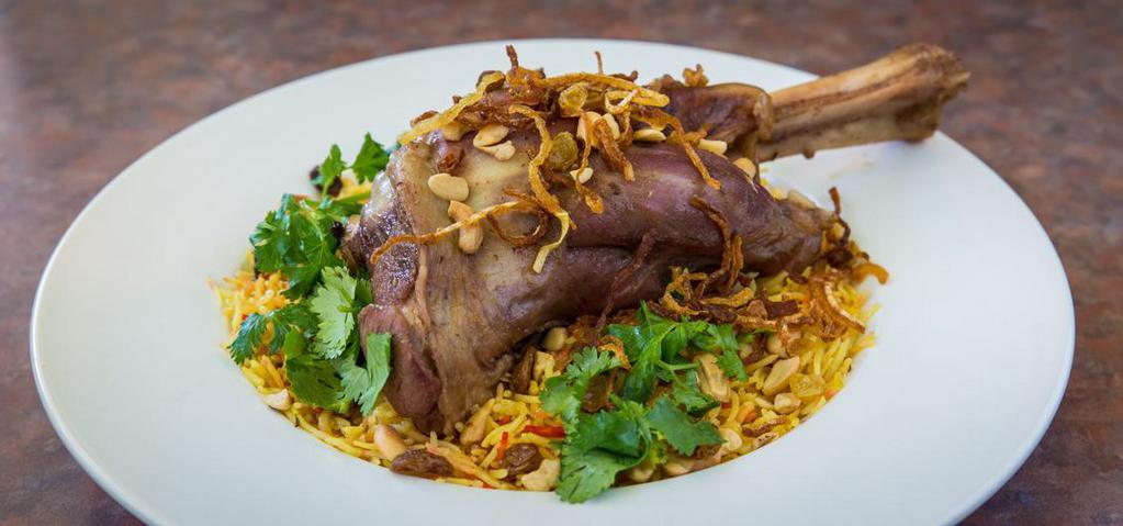 60) Lamb Leg Biryani · Braised lamb leg with fragrant biryani rice, spices, raisins, nuts, mint, cilantro, and fried onions.