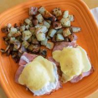 Eggs Benedict · Two poached eggs over English muffin and ham.  Served home fries and hollandaise sauce.
