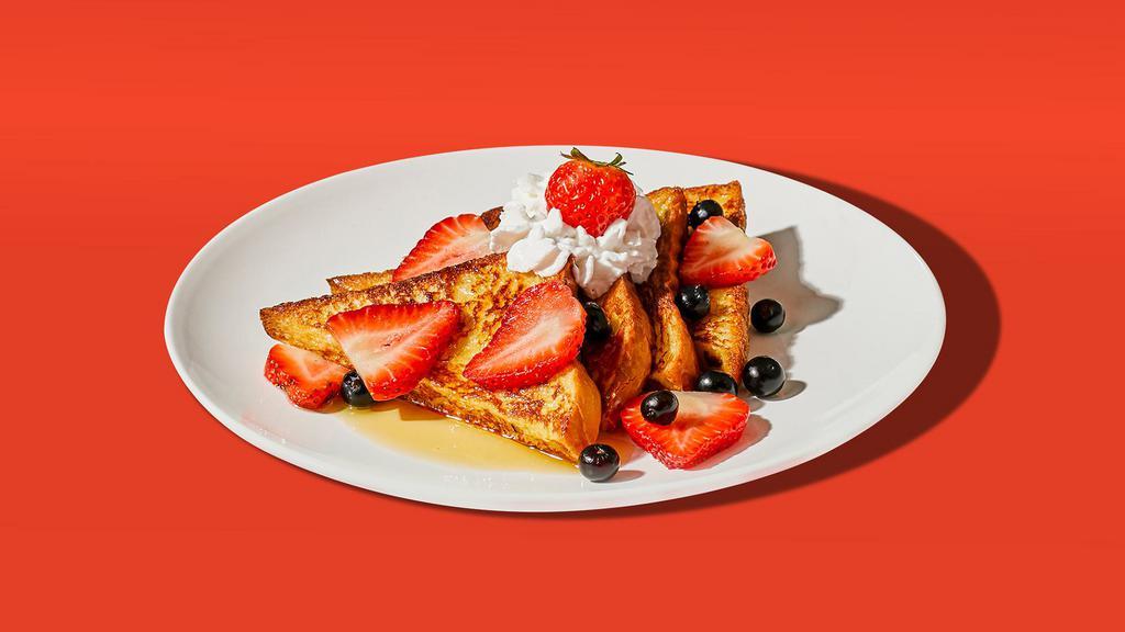 Mixed Berry French Toast · Two slices of egg-washed french toast topped with strawberries, blueberries, whipped cream, maple syrup, and butter.