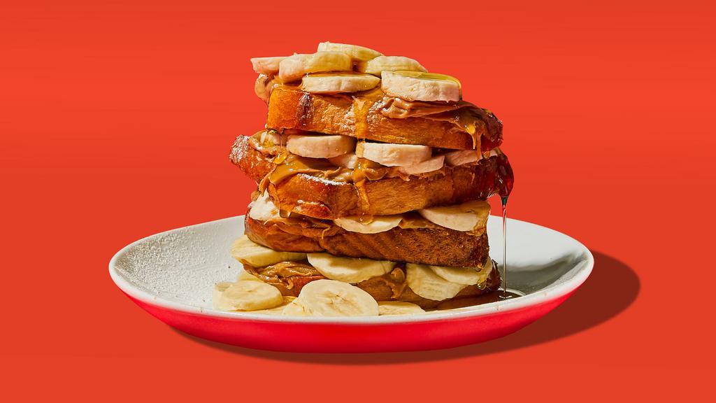 Banana Peanut Butter Stuffed French Toast · Two slices of egg-washed french toast with banana, peanut butter, maple syrup and butter.
