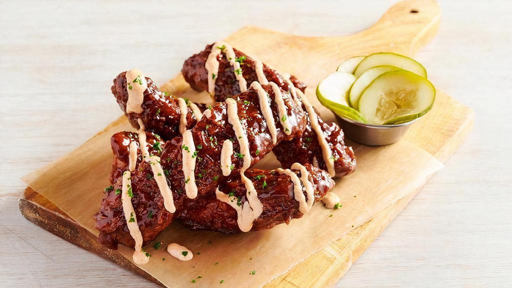 Aussie Twisted Ribs · Our tender St. Louis Ribs fried Outback-style then tossed in tangy BBQ sauce and drizzled with our spicy signature bloom sauce. Garnished with spicy house-made pickles.