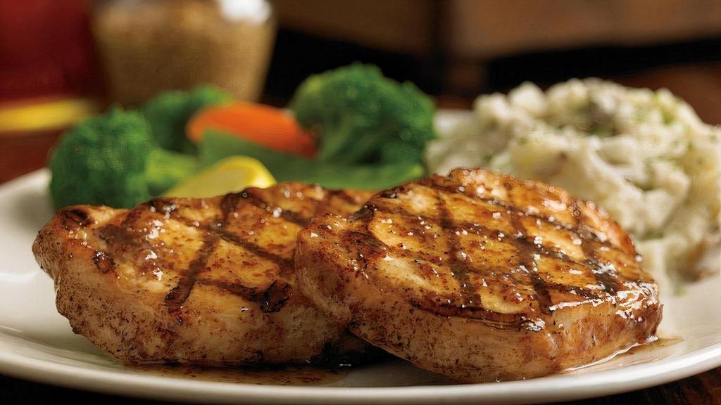 Grilled Pork Chop* · A grilled pork chop served with two freshly made sides and Creole marmalade.