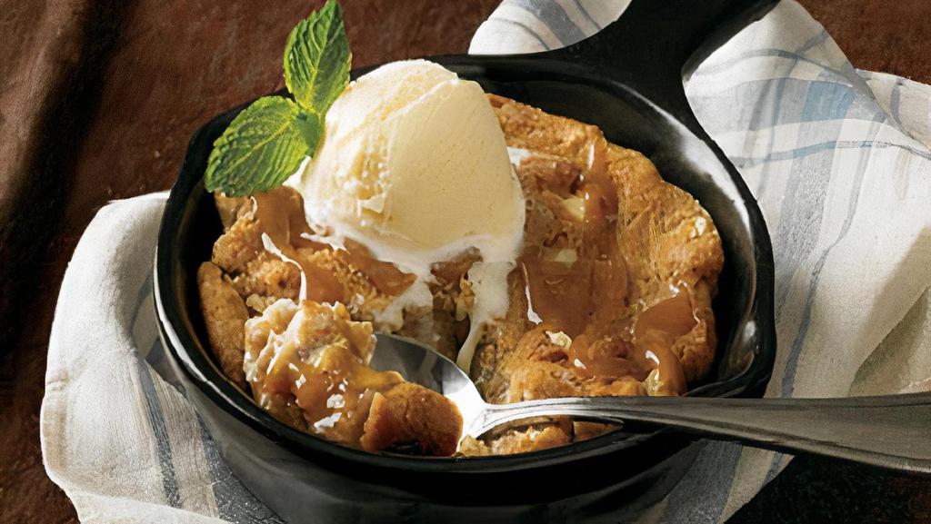 Salted Caramel Cookie Skillet** · A warm salted caramel cookie with pieces of white chocolate, almond toffee and pretzels, toasted in a skillet and served with vanilla ice cream.