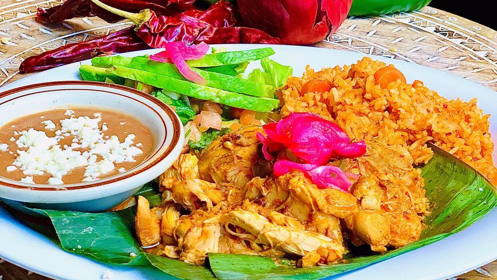 Pollo Pibil De Yucatan · Tender slow-cooked chicken, marinated in a citrus achiote blend, served w/ rice & refried beans, shredded lettuce, pico de gallo & avocado slices.