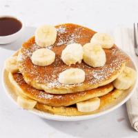 Banana Pancakes · Two fluffy buttermilk pancakes topped with sliced bananas, and served with maple syrup and p...