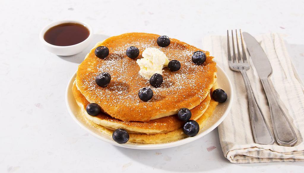 Blueberry Pancakes · Two fluffy buttermilk pancakes topped with fresh blueberries, and served with maple syrup and powdered sugar.