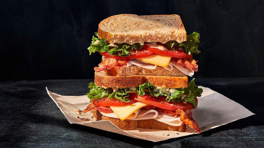 Bacon Turkey Bravo Sandwich · Whole (1010 Cal.), Half (500 Cal.) Oven-roasted turkey breast raised without antibiotics, Applewood-smoked bacon, smoked Gouda, emerald greens, vine-ripened tomatoes, signature sauce , salt and pepper on Tomato Basil Bread. Allergens: Contains Wheat, Milk, Egg