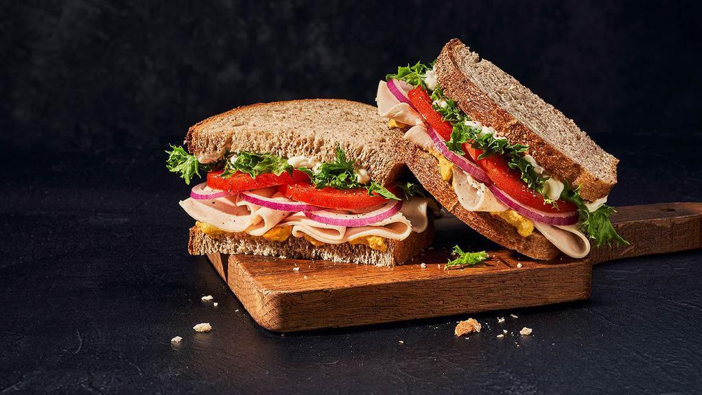 Deli Turkey Sandwich · Whole (590 Cal.), Half (300 Cal.) Oven-roasted turkey breast raised without antibiotics, emerald greens, vine-ripened tomatoes, red onions, mayo, spicy mustard, salt and pepper on Country Rustic Sourdough. Allergens: Contains Wheat, Egg