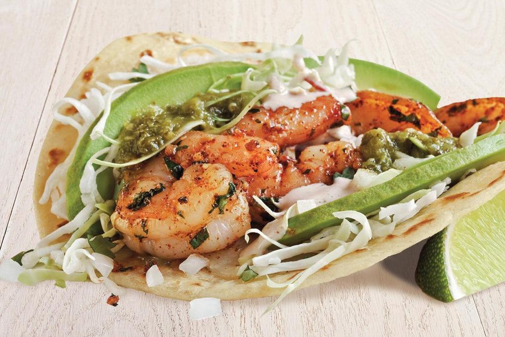 Salsa Verde Grilled Shrimp Taco (A La Carte) · Pan-seared shrimp served on a flour tortilla topped with salsa verde, Hass avocado slices, melted cheese, creamy chipotle sauce, cilantro/onion mix and cabbage.