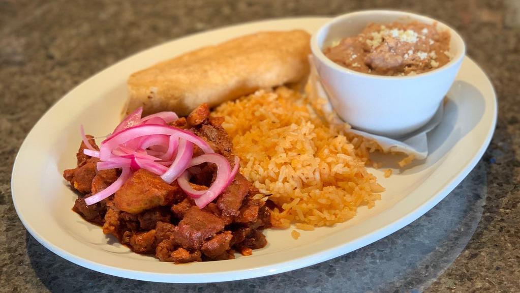 Pork Adobo · Tender chunks of pork smothered in a deep and flavorful red sauce, pickled red onions, rice and charro beans.