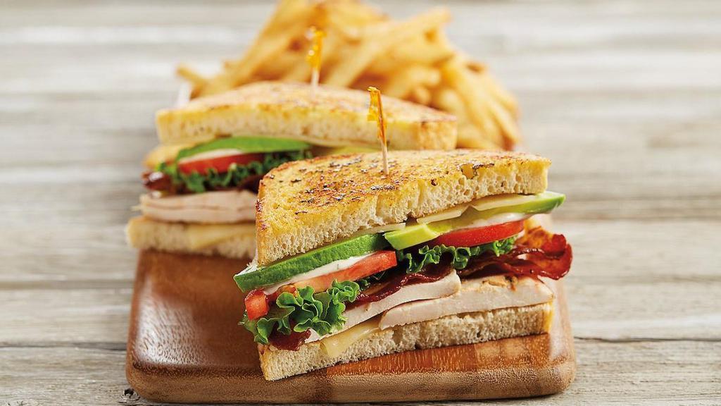 California Chicken Club Sandwich · Seasoned grilled chicken | applewood smoked bacon | avocado | melted swiss cheese | lettuce | tomatoes | roasted garlic aioli | toasted sourdough bread | served with fries