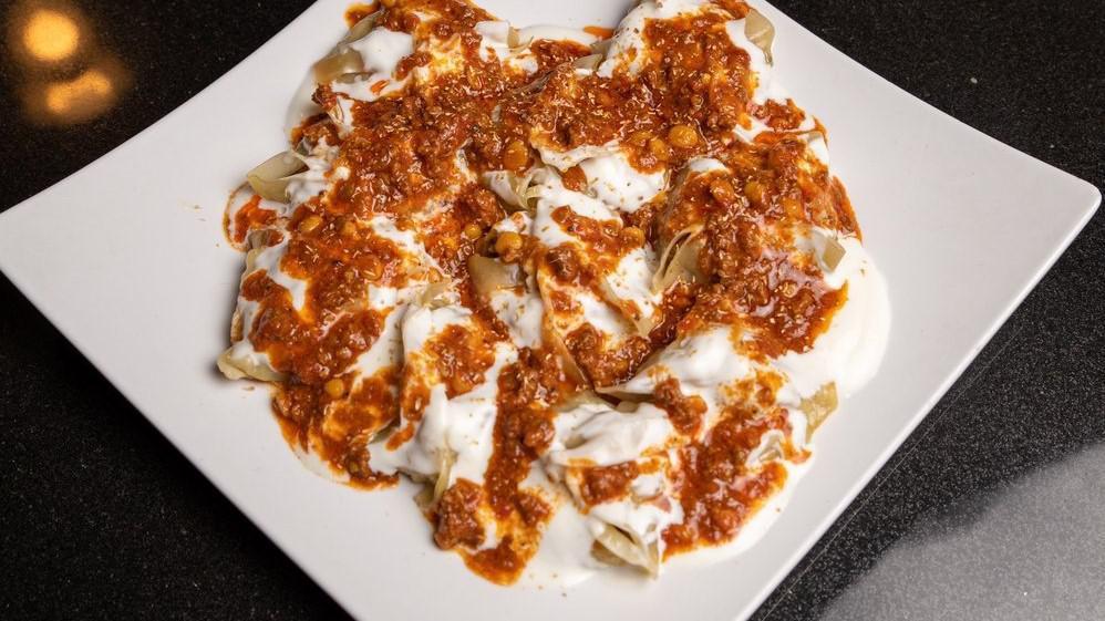 Mantoo · Handmade dumplings stuffed with minced beef, onion, and spices. Served on bed of garlic yogurt and dry mint sauce. Topped with minced beef and split pea in tomato sauce.
