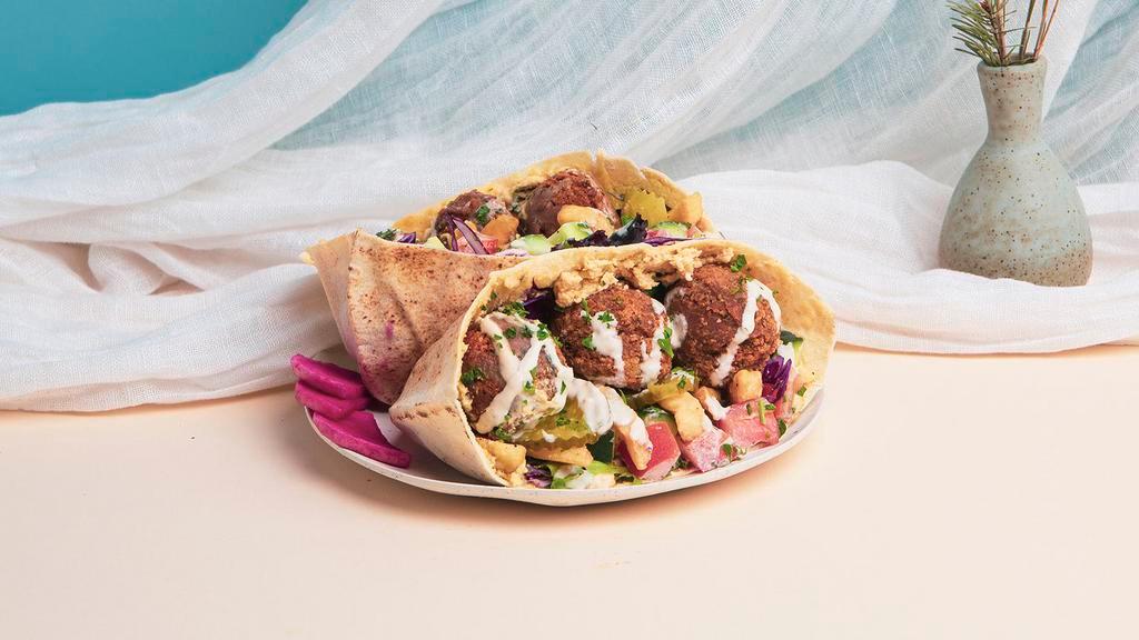 Ultimate Falafel Pita Sandwich · Falafel with hummus, french fries, shredded cabbage, diced tomato and cucumber, and a tahini drizzle wrapped up in a fresh pita.