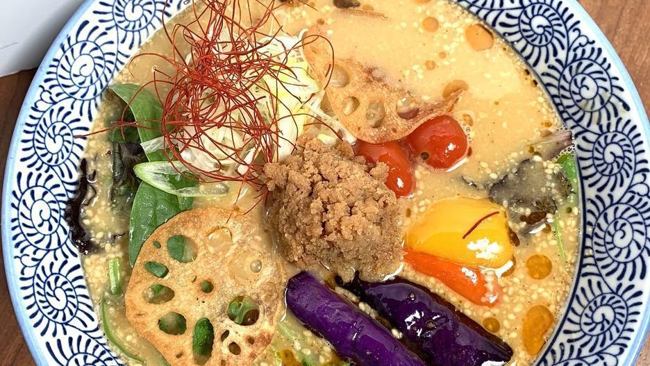 Vegan Curry Tantan Ramen · Veggie Spicy Curry TanTan Soup with Vegan Noodle.
Topped with Eggplant, Bell Pepper, Tokyo Negi, Cherry Tomato, Spring Mix, Lotus Root Chips, Soybean Flakes, Shredded Chili Pepper, Sesame
