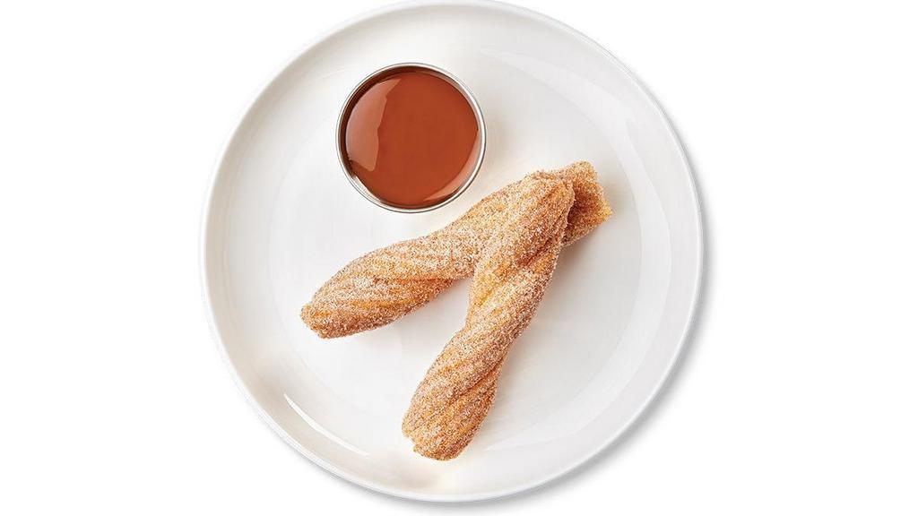 Churro with Dulce de Leche Dipping Sauce · One churro cut in half and served with a side of dulce de leche dipping sauce
